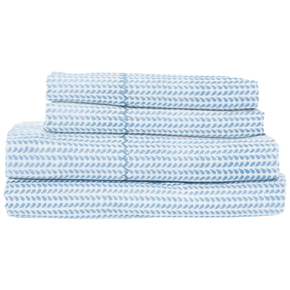 The Cinde Light Indigo Bedding Collection by John Robshaw features cotton percale sheets with a blue and white repeating leaf pattern, neatly folded and stacked.