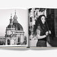 The Assouline Sicily Honor coffee table book lies open, showing a domed building in black-and-white on the left and a woman in a lace headscarf on the right, capturing the refined elegance of Taormina.