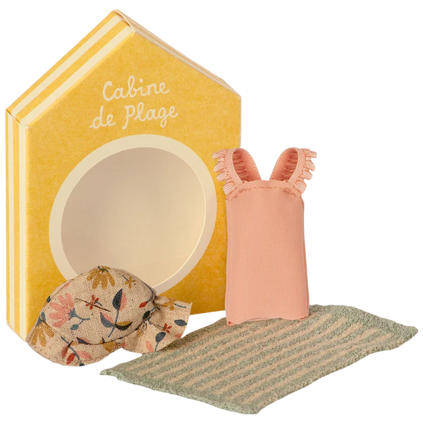 A **Maileg Beach Set for Big Sister Mouse** from the brand **Maileg**, featuring a yellow box labeled "Cabine de Plage" with an empty circular window, a small floral sunhat, a pink dress, and a striped mat.