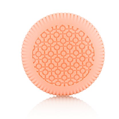 A round, light orange item with a patterned surface and ridged edges from Baobab Collection Women Body Wellness Collection by Baobab, shown on a white background, evoking the softness of a women’s floral fragrance.