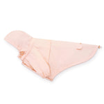 The Foggy Dog's light pink Dog Raincoat, featuring a waterproof design, pocket, hood, and adjustable drawstrings, is laid flat on a white background.