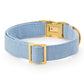 The Foggy Dog Blue Chambray Dog Collar features light blue chambray fabric with a gold-tone metal buckle and D-ring for timeless style, shown on a white background.