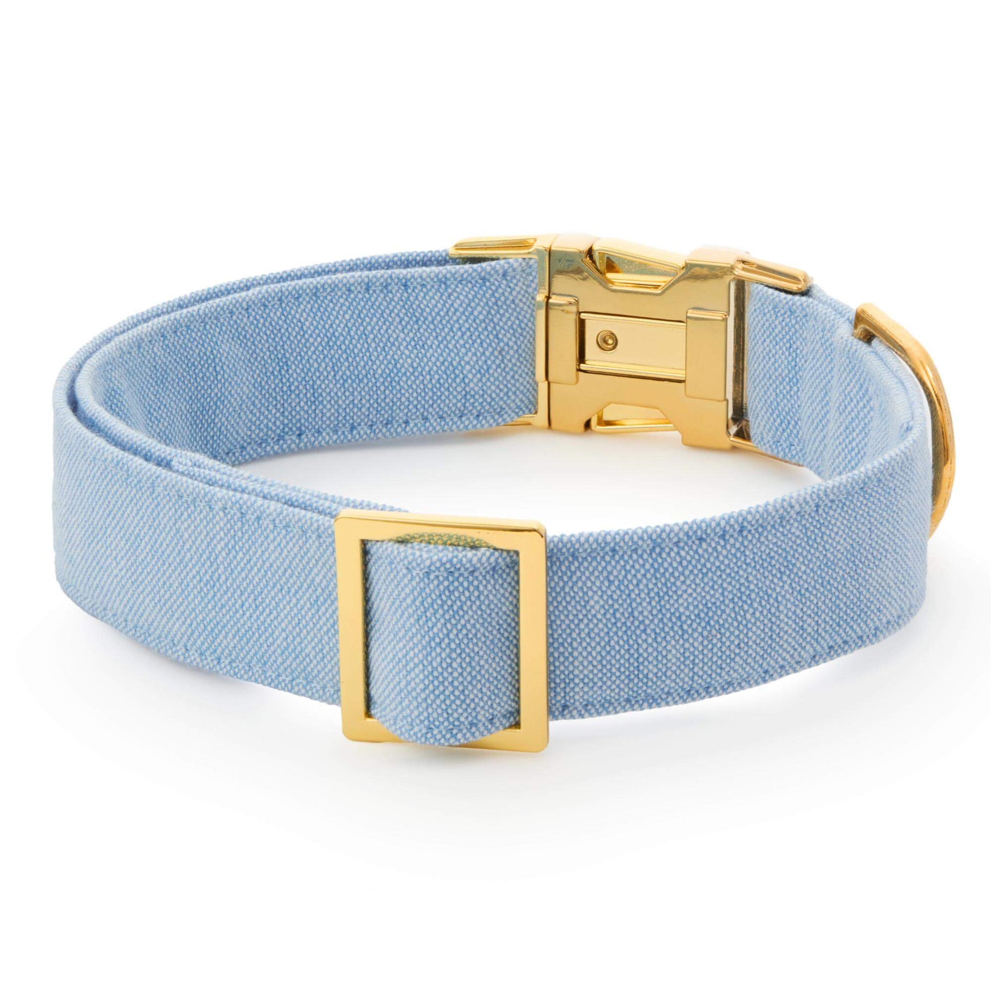 The Foggy Dog Blue Chambray Dog Collar features light blue chambray fabric with a gold-tone metal buckle and D-ring for timeless style, shown on a white background.