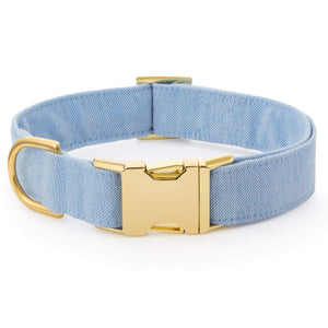 The Foggy Dog Blue Chambray Dog Collar features light blue chambray fabric, a gold metal buckle and D-ring for style and comfort, shown on a white background.