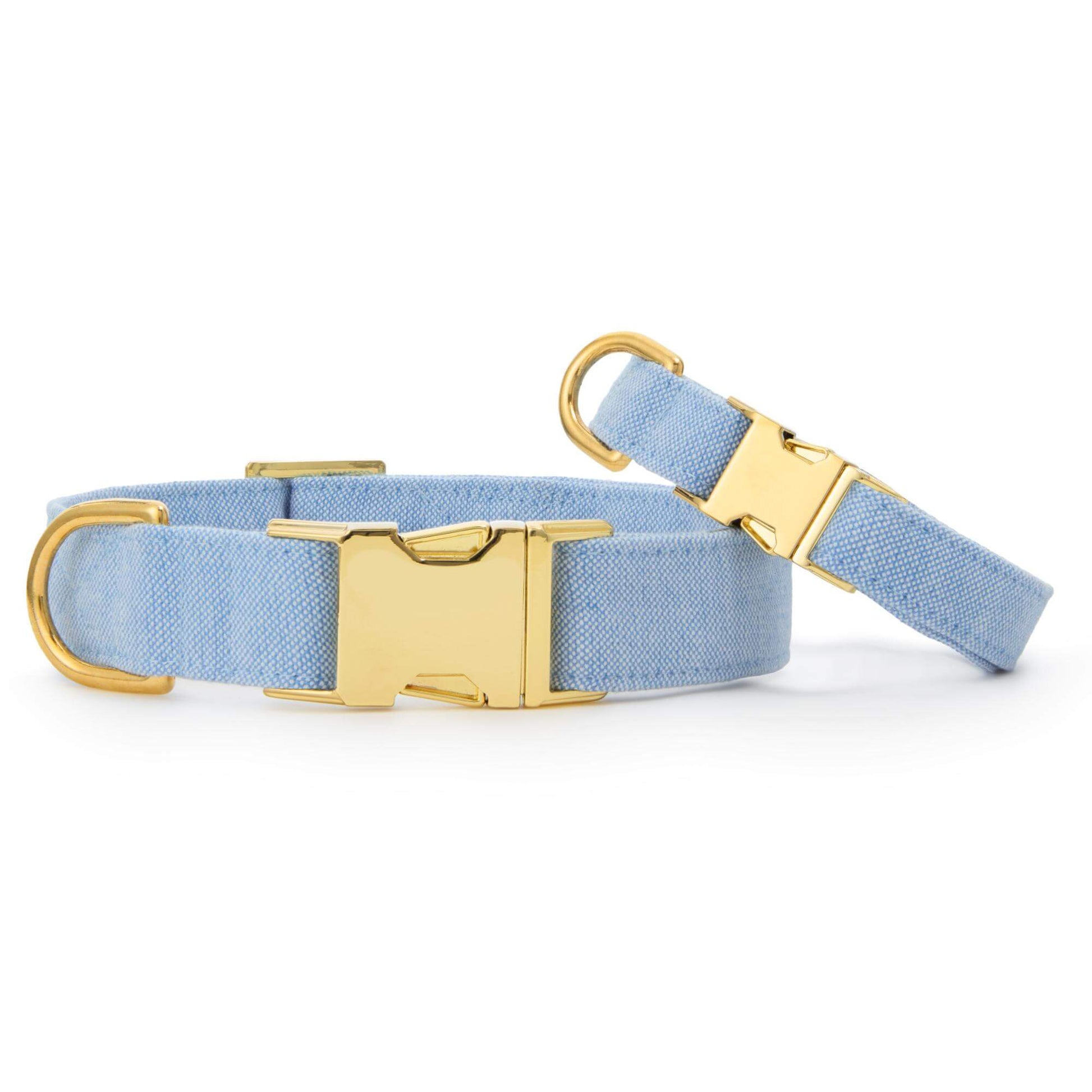 Two Blue Chambray Dog Collars by The Foggy Dog, featuring gold metal buckles and D-rings, are shown on a white background.