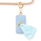 The Foggy Dog’s Waste Bag Dispenser in Blue Chambray features a gold clip and attaches seamlessly to your beige leash, dispensing light blue waste bags through a sturdy metal ring for a chic and stylish pet accessory.