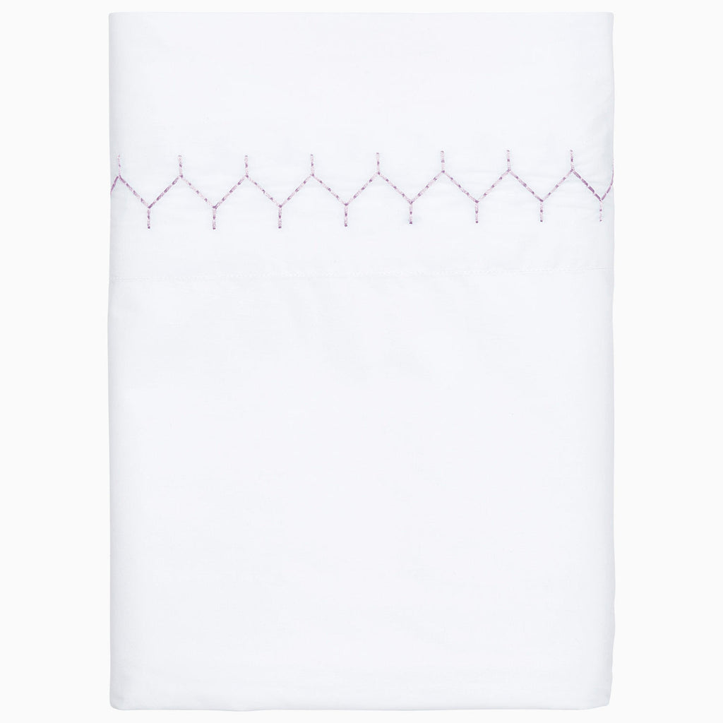 The John Robshaw Stitched Sheet Set in Lavender is crafted from organic cotton percale, featuring a simple hand-embroidered pattern near the top edge.