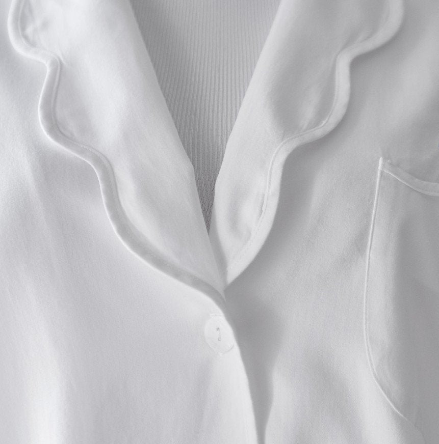 Close-up of the Sue Nightshirt by Haute Home in cotton sateen, with wavy collar, single white button, chest pocket, and ribbed white undershirt—a touch of refined comfort in elegant sleepwear.