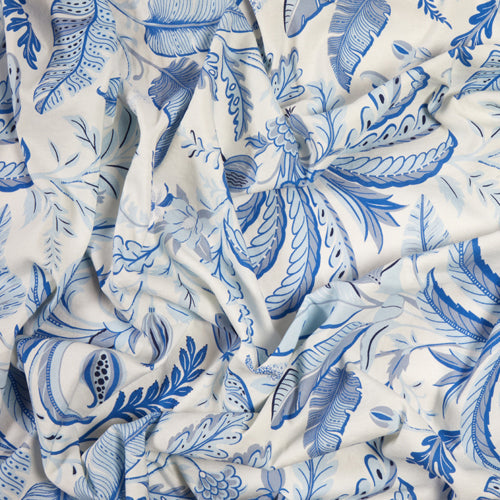 The Palm Beach Tablecloth by Addison Ross features crumpled white fabric with blue botanical and leaf patterns in various shades, adding intricate detail and a touch of elegance to any table setting.