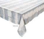 The Kim Seybert Watercolor Stripe White/Blue Linen Collection features a 100% linen rectangular tablecloth with a blue and white pattern and "Tablecloth" printed near the edge—ideal for stylish summer dining.