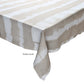 A rectangular table is draped with the Kim Seybert Watercolor Stripe White/Natural Linen Collection tablecloth, featuring beige and white stripes—ideal for summer dining. The image displays "Tablecloth" as a label.