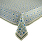 A rectangular table is adorned with the Kim Seybert Majorelle Tablecloth Collection, showcasing blue flowers, green leaves, and striped borders inspired by Indian block print designs.