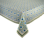 A rectangular table is adorned with the Kim Seybert Majorelle Tablecloth Collection, showcasing blue flowers, green leaves, and striped borders inspired by Indian block print designs.