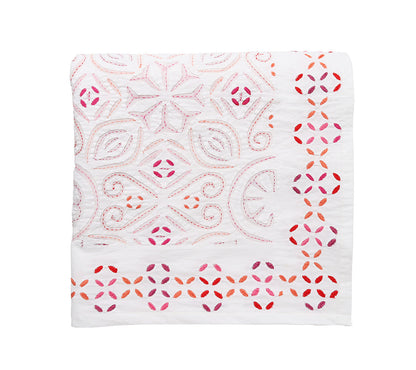 The Malta Tablecloth Collection by Kim Seybert features a folded white tablecloth with pink and red embroidered geometric and floral patterns, perfect for elegant table décor.