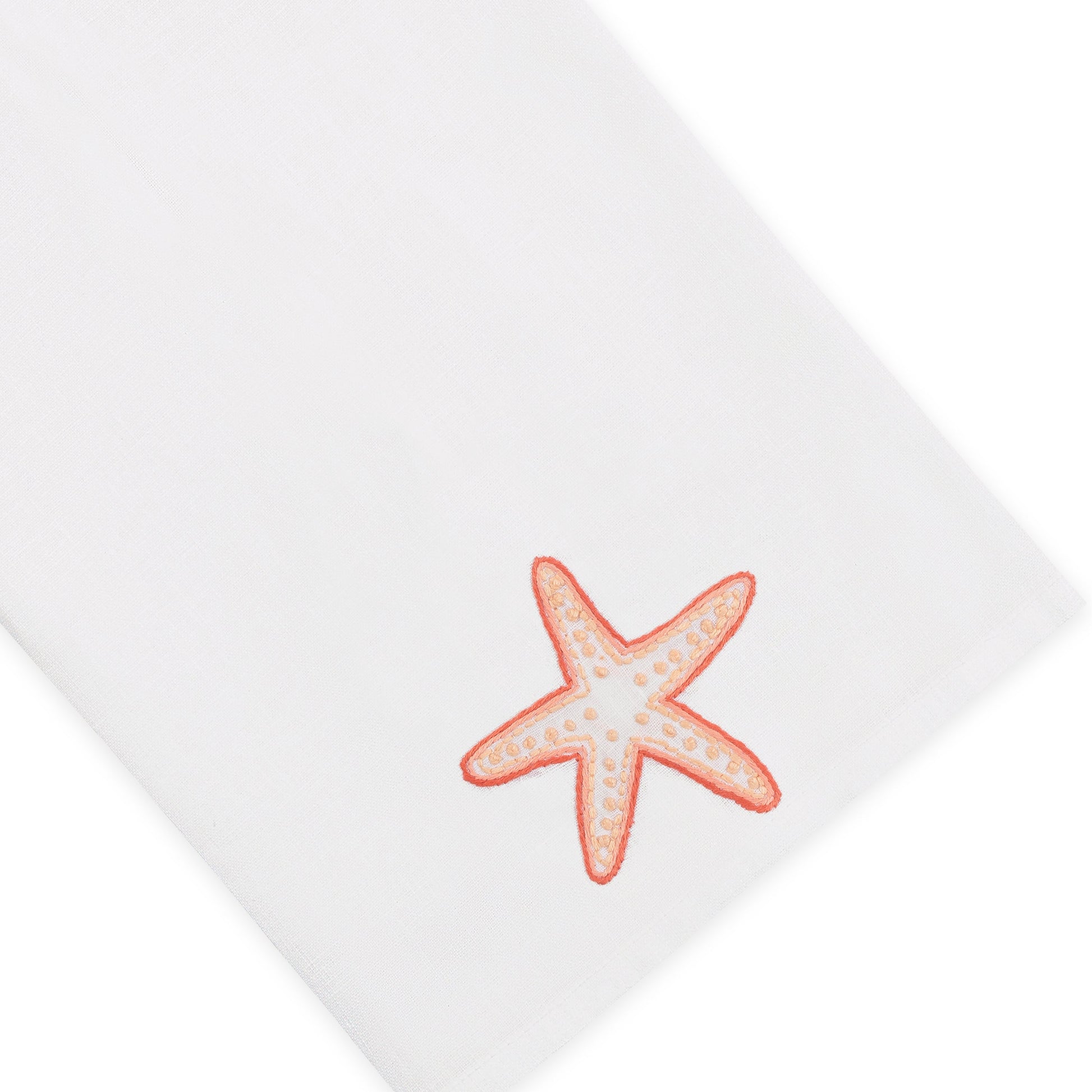 Elevate your home décor with the Haute Home Playful Starfish Bath Collection: a white linen cloth napkin adorned with an embroidered orange starfish in one corner, seamlessly combining elegance and charm.