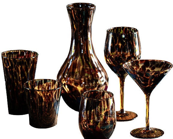 A collection of Juliska Puro Tortoiseshell glassware, including a vase, two types of glasses, a stemmed goblet, and a tumbler, displayed against a white background.