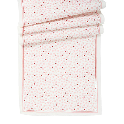 The Juliska "Love You More" Table Runner features a rectangular white design with red and pink small heart patterns and a thin red border—perfect for festive table decor.