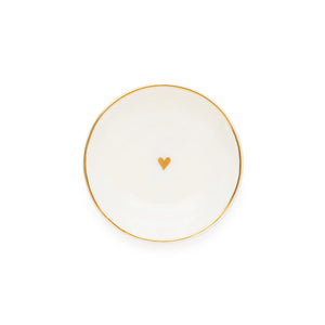 The Sugar Paper Small Round Heart Trinket Tray is a white ceramic dish featuring an elegant gold rim and a delicate gold heart at its center, beautifully photographed on a plain white background to highlight its sophisticated gold details.