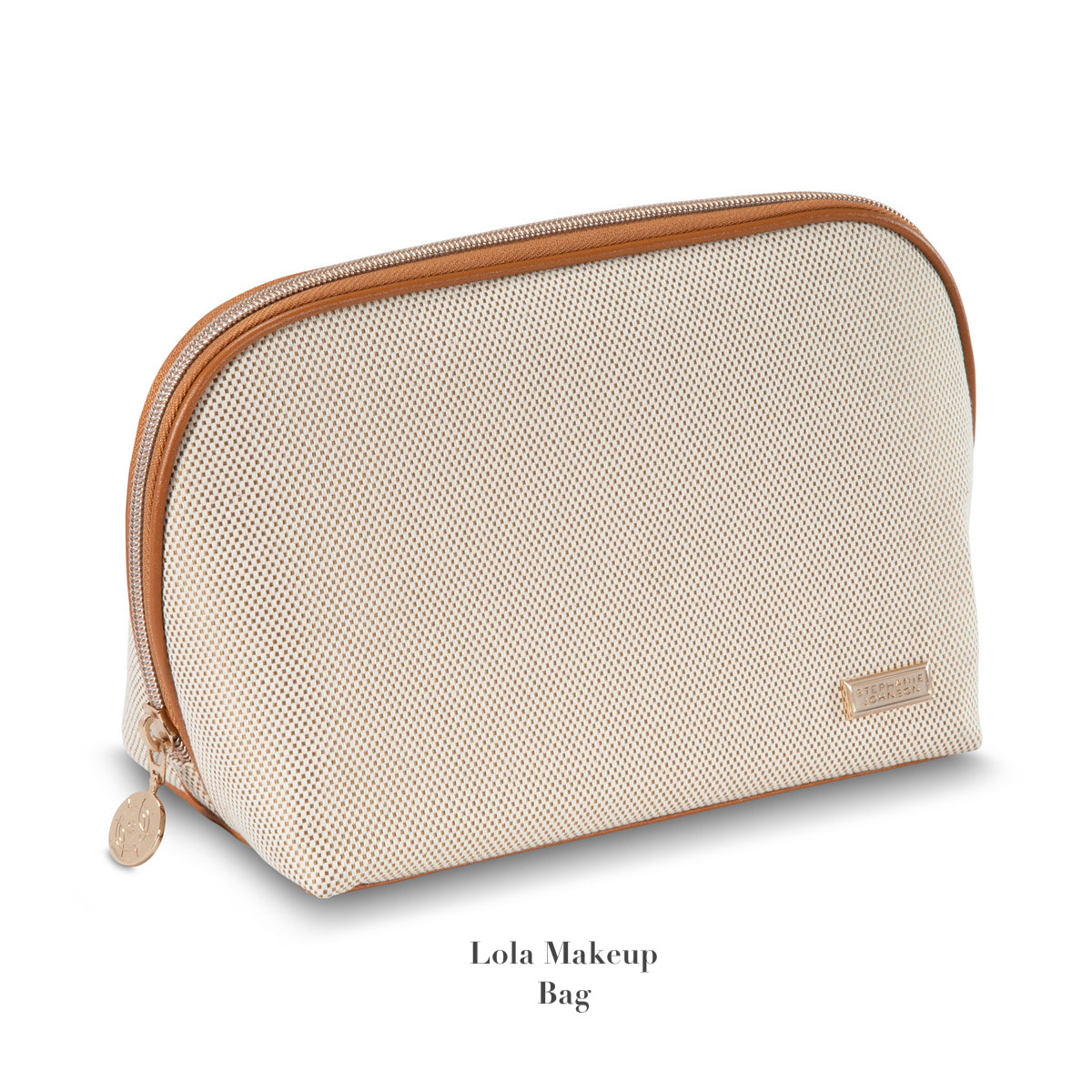 Beige textured "Tropea Travel Collection" makeup bag by Stephanie Johnson, with brown zipper and branded metal label, standing upright on white background. Removable compartments for easy organization. Text: "Lola Makeup Bag.