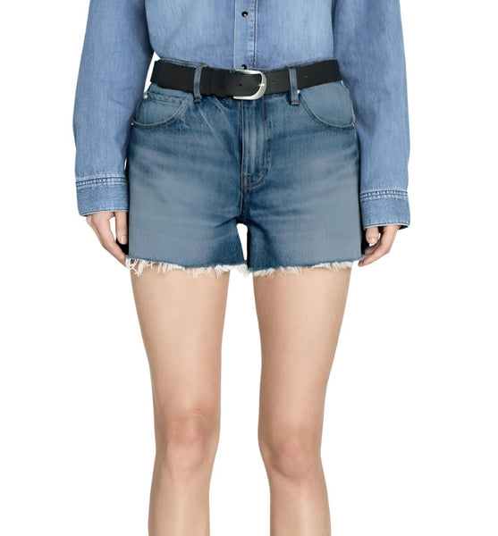 A person wearing a blue denim jacket and Frame high-rise denim shorts, paired with a black belt, isolated on a white background.