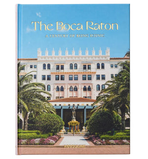 Assouline’s hardcover book, "The Boca Raton: A Century of Being Iconic," features a photo of the historic luxury resort, showcasing its grand white building, palm trees, and a statue on the cover.