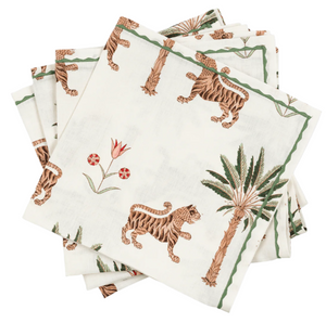 The Matouk Tiger Palm Tabletop Collection features a stack of white napkins with Schumacher designs, showcasing jungle motifs like tigers, palm trees, and green and brown flowers.