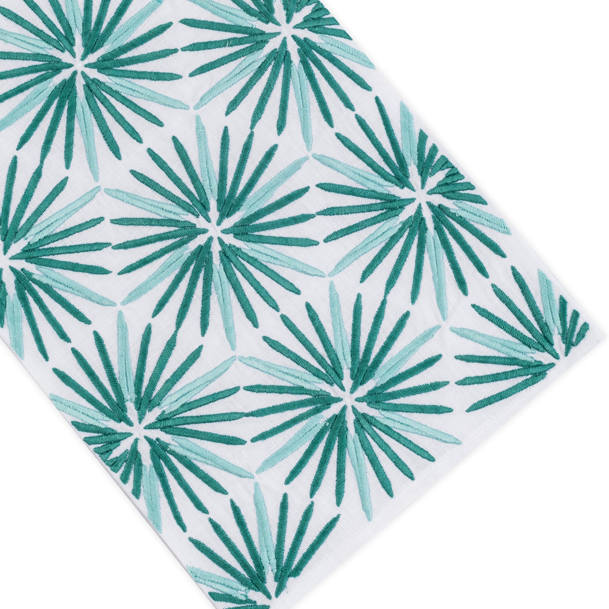 The Radiant Bath Collection by Haute Home features white cloth made from premium linen, adorned with a repeating pattern of green, starburst-shaped palm leaves shown at a slight angle—making it a stunning addition to contemporary home décor.