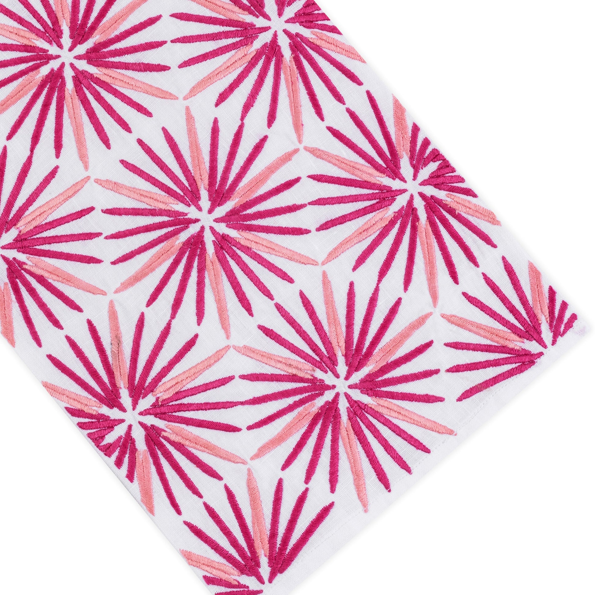 The Radiant Bath Collection by Haute Home showcases a crisp white linen surface adorned with a repeating pattern of pink and red starburst shapes, arranged diagonally to bring a vibrant flair to sophisticated home décor.