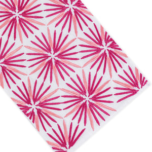 The Radiant Bath Collection by Haute Home showcases a crisp white linen surface adorned with a repeating pattern of pink and red starburst shapes, arranged diagonally to bring a vibrant flair to sophisticated home décor.
