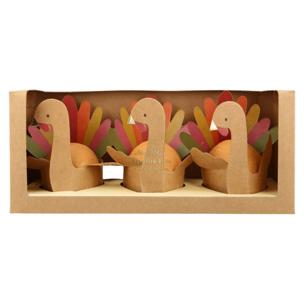 Three Meri Meri Turkey Surprise Balls featuring 3D turkey designs with colorful tails are neatly arranged in a cardboard box with a transparent front, making them perfect as party bag gifts.