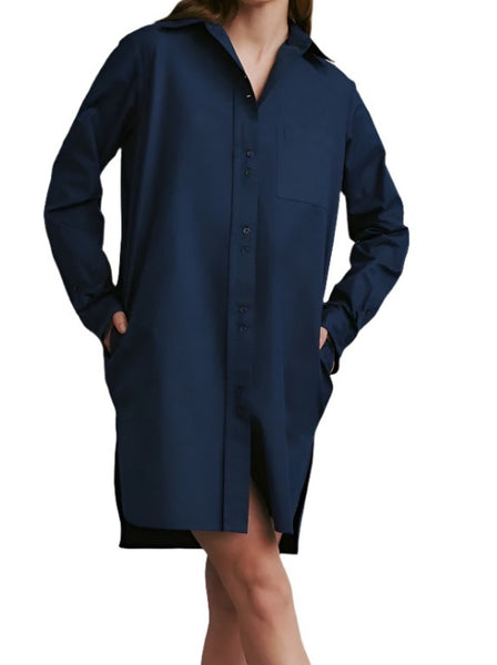 Person wearing an oversized, long-sleeve, navy blue TWP Ma House Dress with hands in pockets. Face is not visible. Studio background.