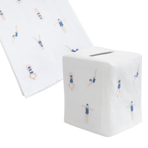 The Freestyle Swim Bath Collection by Haute Home features a white tissue box cover and matching towel, hand embroidered with navy-clad swimmers in diving poses on fine Italian linen.