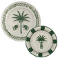 Two ceramic plates from Johanna Ortiz's Casa Dark Jungle Dinnerware Collection: the larger features a palm tree with two monkeys, the smaller has a palm tree and green border—exquisite hand-painted pieces inspired by Carmen de Viboral’s heritage.