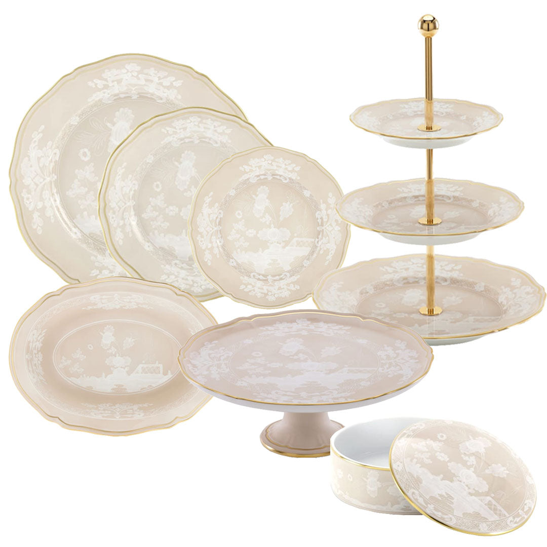 The Oriente Italiano Meringa Dinnerware & Serveware Collection by Ginori 1735 features cream porcelain plates, a cake stand, tiered tray, and covered dish adorned with gold trim and delicate floral patterns.