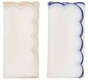 The Kim Seybert Lune Napkin Set features two folded white napkins—one with gold scalloped edges and one with blue—side by side on a white background, perfect for adding elegance to any table setting.