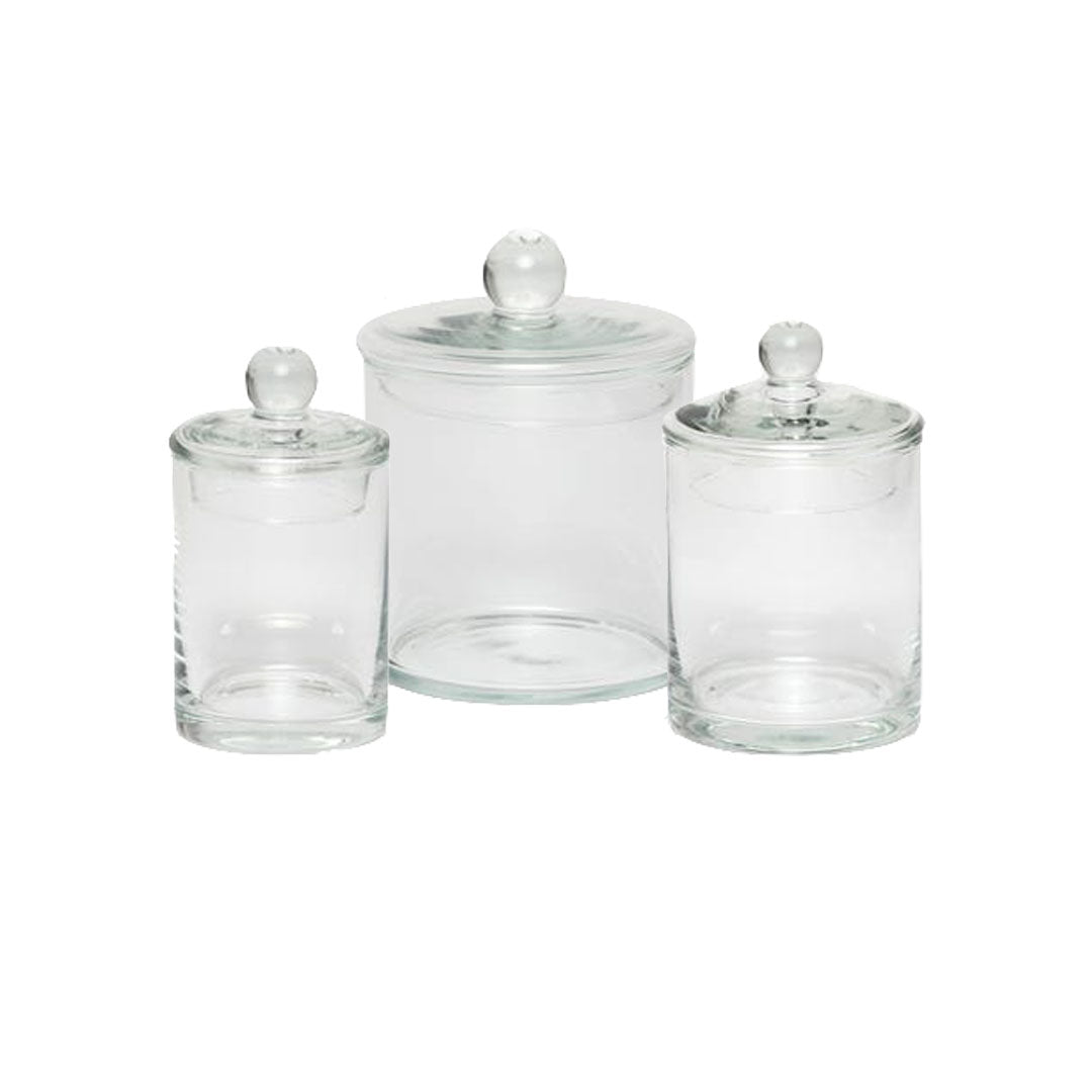 The Darby Clear Canister Collection by Pigeon & Poodle features three glass jars with round-handled lids in assorted sizes, ideal for bathroom organization or versatile storage. Displayed on a plain white background.