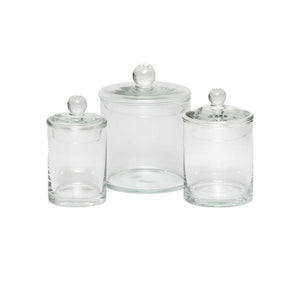 The Darby Clear Canister Collection by Pigeon & Poodle features three glass jars with round-handled lids in assorted sizes, ideal for bathroom organization or versatile storage. Displayed on a plain white background.
