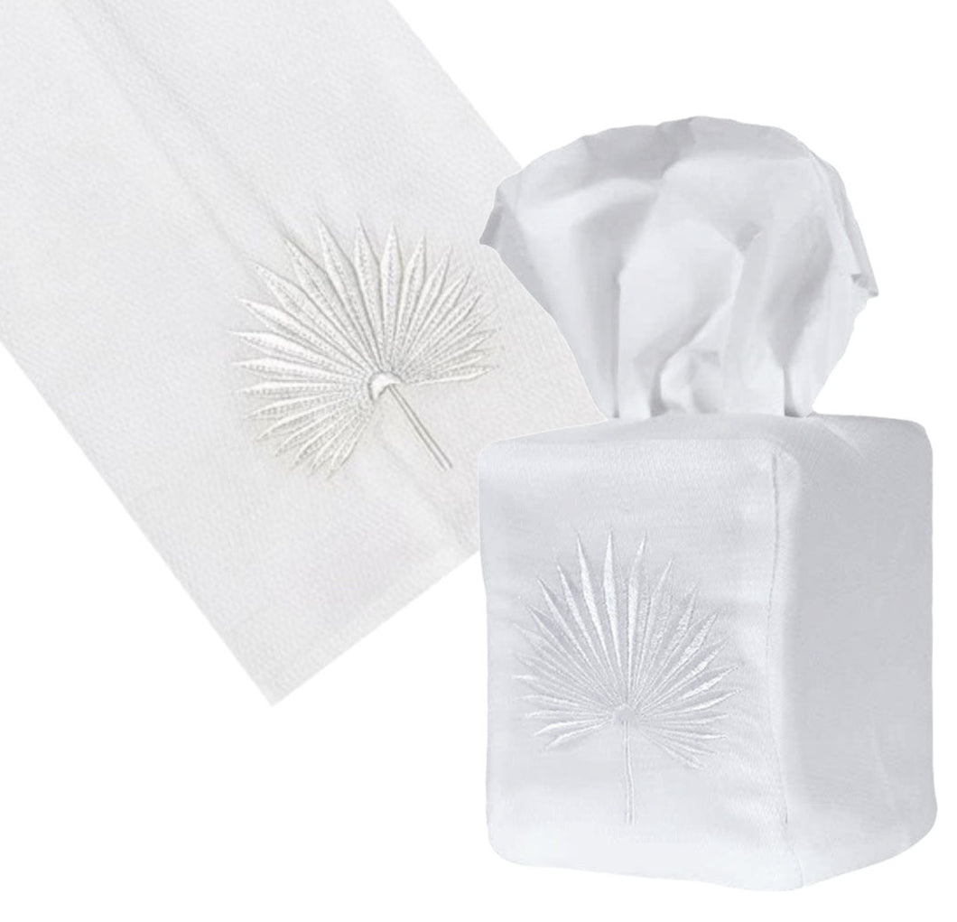 The Haute Home Huck White Palm Leaf Bath Collection features a cotton Huck pique tissue box cover and napkin, both adorned with machine embroidered palm leaf designs for a refined touch.
