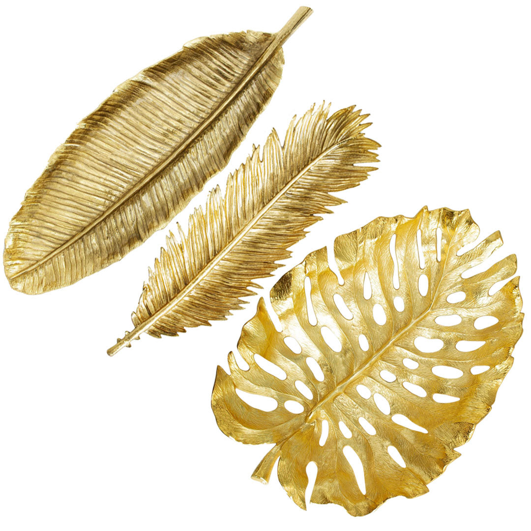 Three metallic gold leaves in various shapes and sizes from Michael Aram's New Leaves Serveware Collection are displayed on a white background, highlighting handcrafted, nature-inspired luxury home accents.