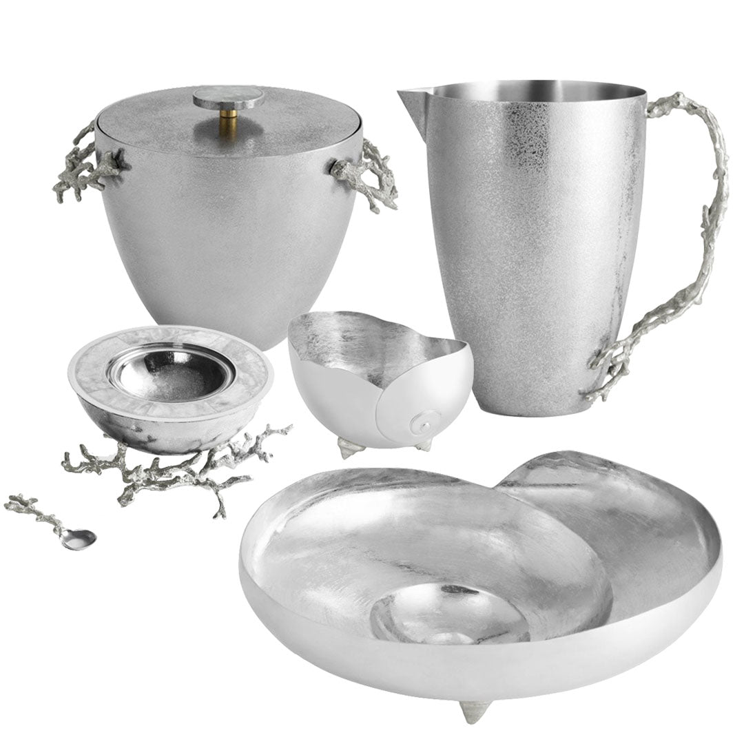 The Michael Aram Ocean Reef Serveware and Barware Collection features five silver and white pieces with textured surfaces and branch-inspired handles, including a pitcher, covered vessel, bowl, dish, and spoon—ideal for coral reef-themed decor.