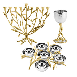 Items from the Michael Aram Olive Branch Judaica Collection—including a gold menorah, a matching gold and silver goblet, and a silver Seder plate with gold accents—are displayed against a white background.
