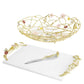 The Michael Aram Wildflower Serveware Collection features a gold wire centerpiece basket with handcrafted wildflowers, an artisanal marble cheeseboard, a knife, and gold floral handles.