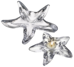 Two starfish-shaped holders from the Simon Pearce Starfish Glassware Collection—one empty, one with a lit tealight—rest on a white background. These make perfect gifts for summer hosts or coastal gatherings.