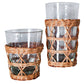 The Seagrass Rattan Cage Tumbler Collection by Be Home features two clear glass tumblers with woven wicker sleeves, blending rustic charm and modern style—shown side by side in different heights.