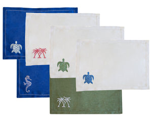 The Coastal Linen Placemat Set by Pink House Mustique includes four rectangular placemats—two blue, two green—with white borders and embroidered sea creatures or palm trees, adding a charming beach-inspired look to your table.