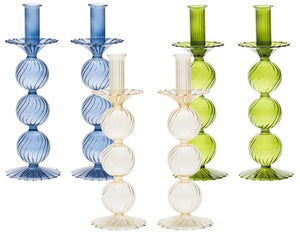 The Kim Seybert Iris Tall Candle Holder Set features five ribbed, hand-blown glass candlestick holders with stacked spheres and scalloped bases in blue, clear, and green, displayed upright against a white background.
