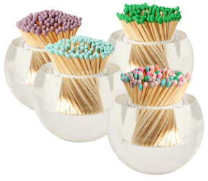 The Acrylic Match Striker Collection by Tart by Taylor includes four clear glass jars of wooden matches with pastel tips—purple, green, blue, and a pink/blue/green mix—each topped with an acrylic striker for a chic coffee table accent.