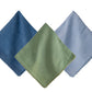 Three Berry Trim Napkin Collection napkins by Juliska, in blue, green, and light blue, are arranged overlapping on a white background.