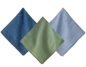 Three Berry Trim Napkin Collection napkins by Juliska, in blue, green, and light blue, are arranged overlapping on a white background.