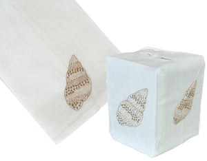 The Speckled Conch Bath Collection by Haute Home features a cream Italian linen tissue box cover and matching towel, each hand-embroidered with an elegant brown seashell design.